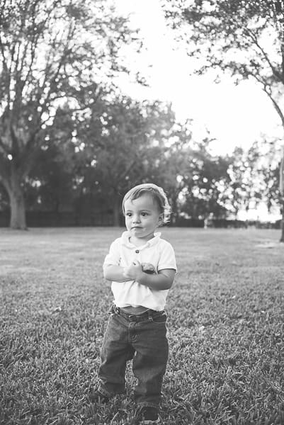 little boy standing in grass in black and white