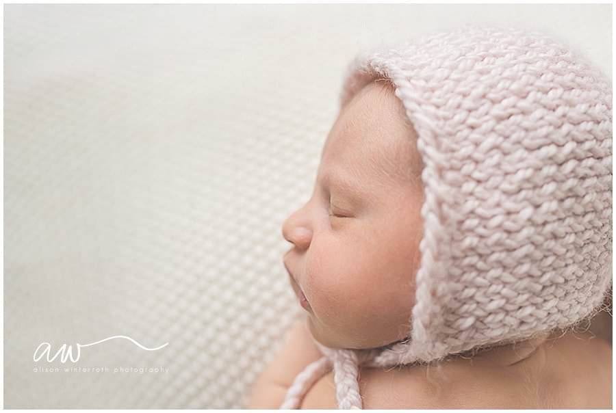 new born baby wearing a light pink bonnet