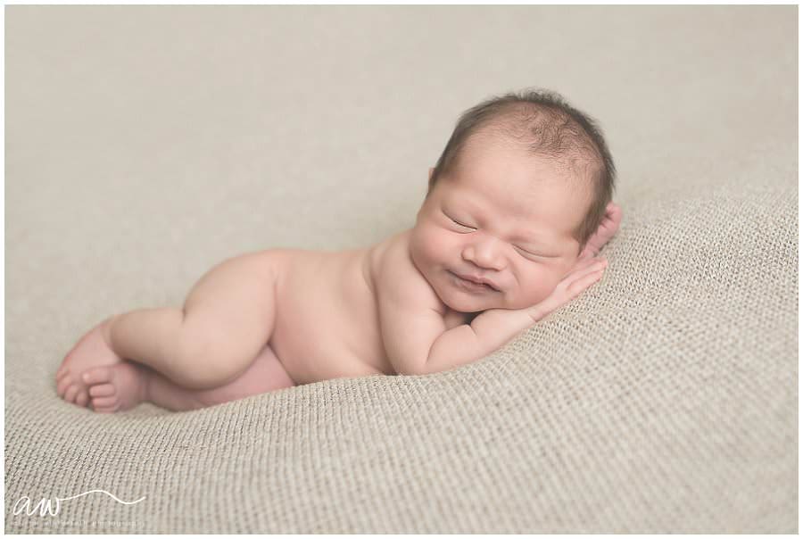 newborn smiling on a blanket.