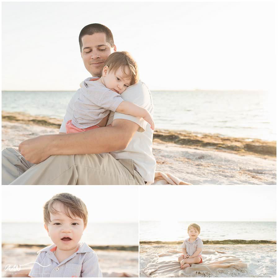 One year old boy snuggling with his dad at at the beach.