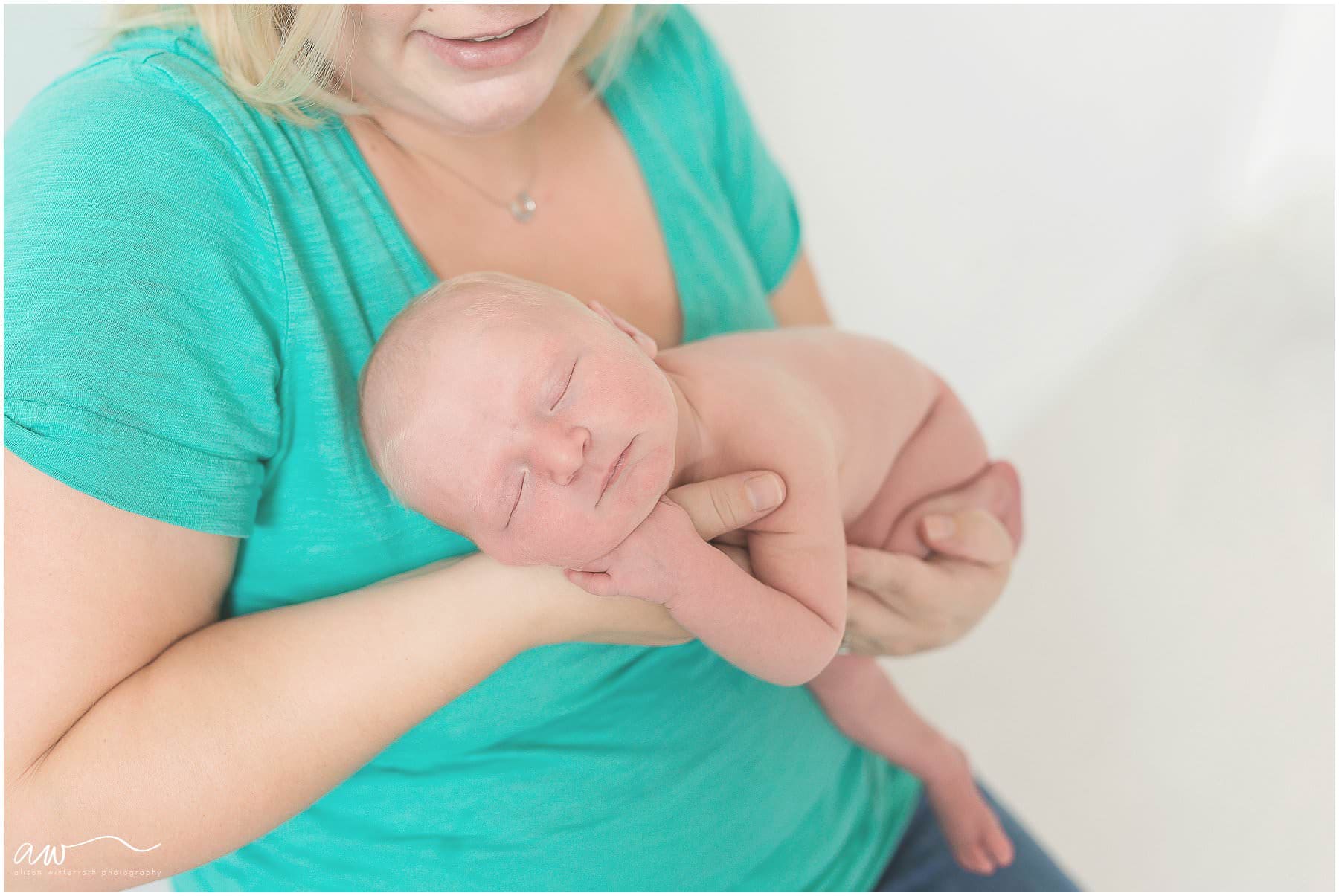 newborn baby smiling, being held by her mommy.