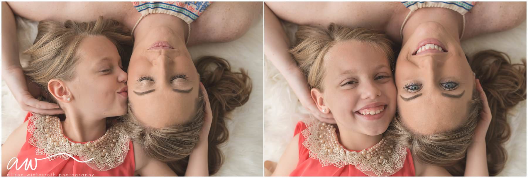 A mom and her daughter laying on a rug holding each other