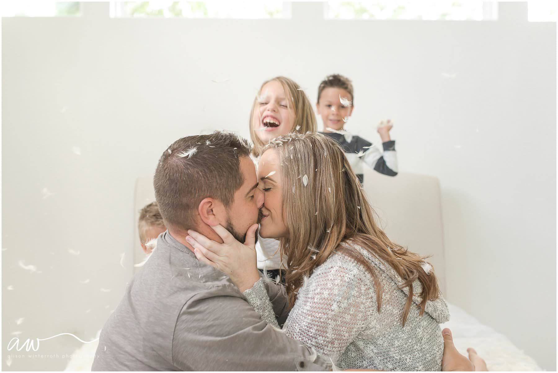 Mom and dad kissing during a pillow fight