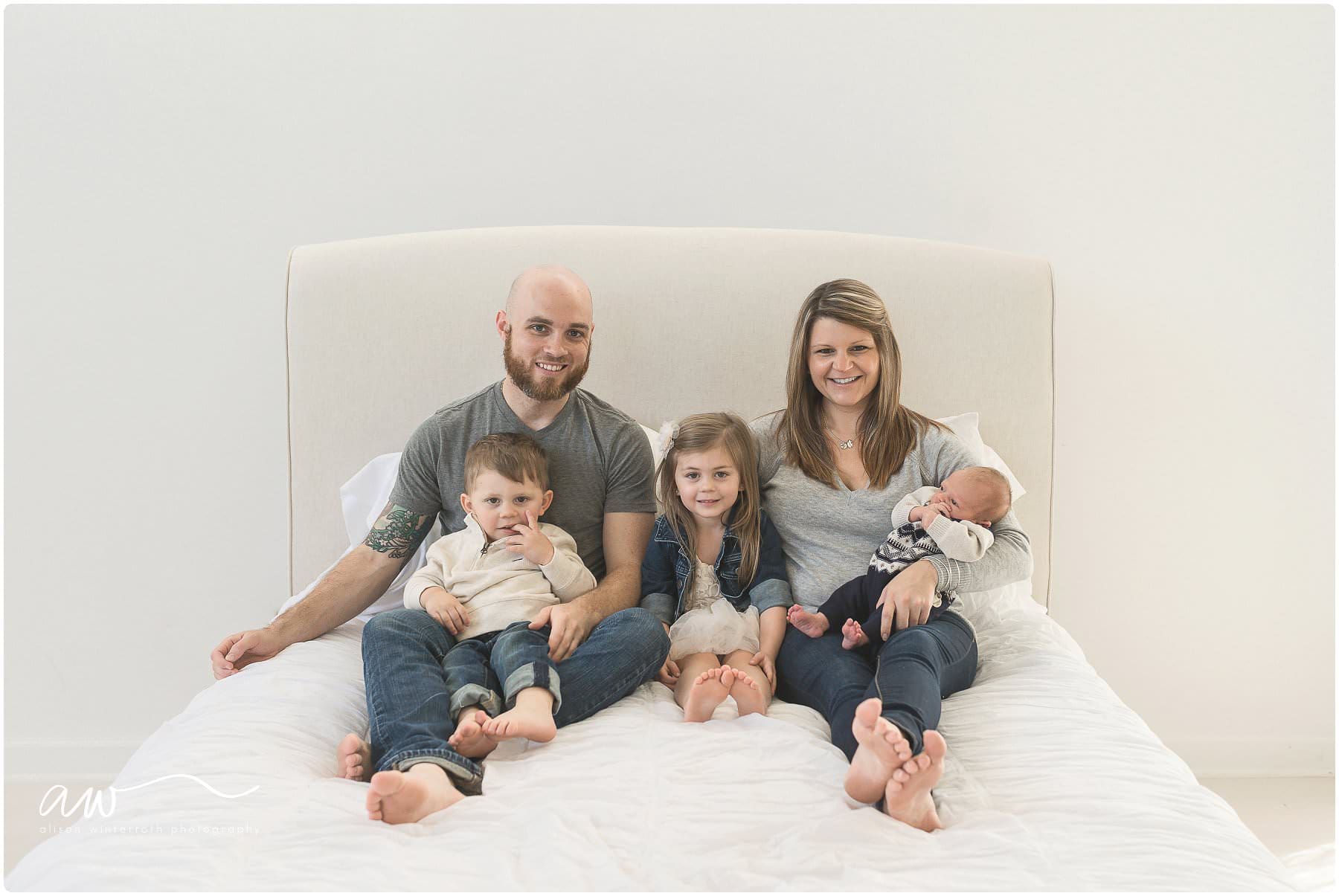 a family with two sons and a daughter on a bed