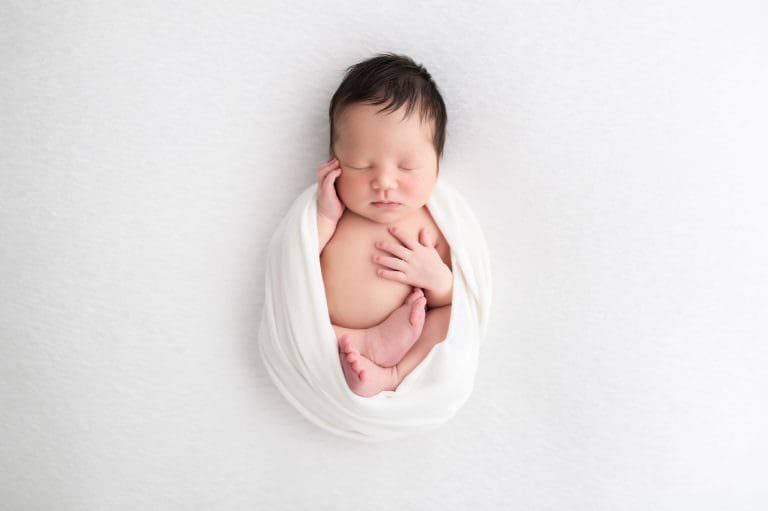A new born sleeping on a neutral blanket