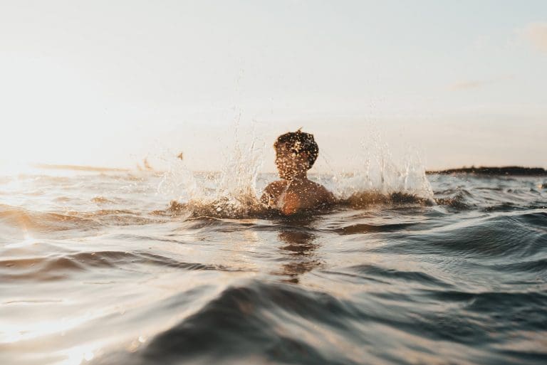boy splashing in the water at sunset
