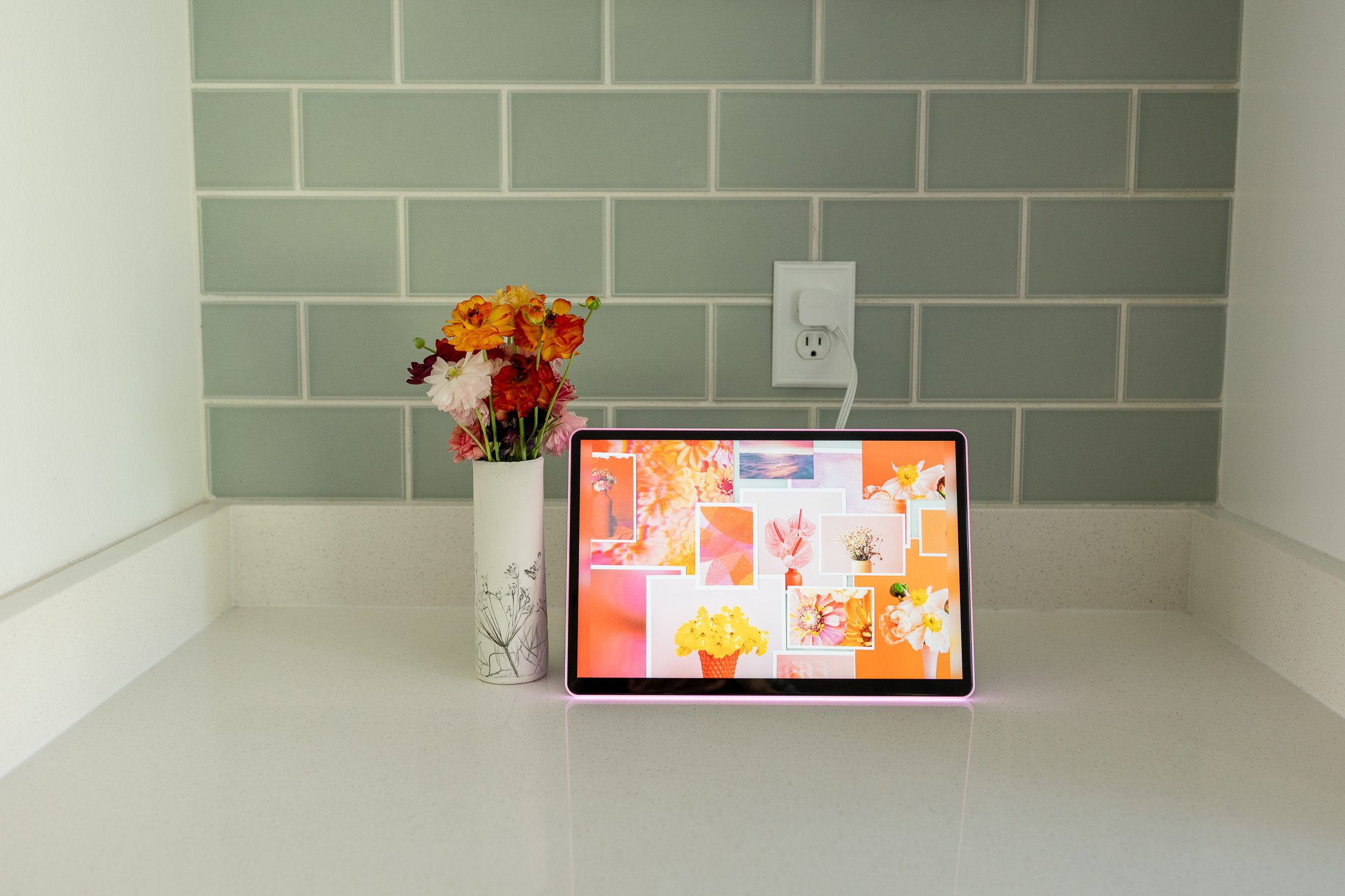 one digital photo frame in front of a green tile background on a white counter